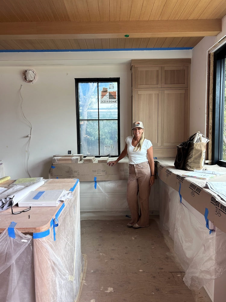 Interior designer Joey Snow standing in her studio during renovation, surrounded by cabinetry samples and construction materials.