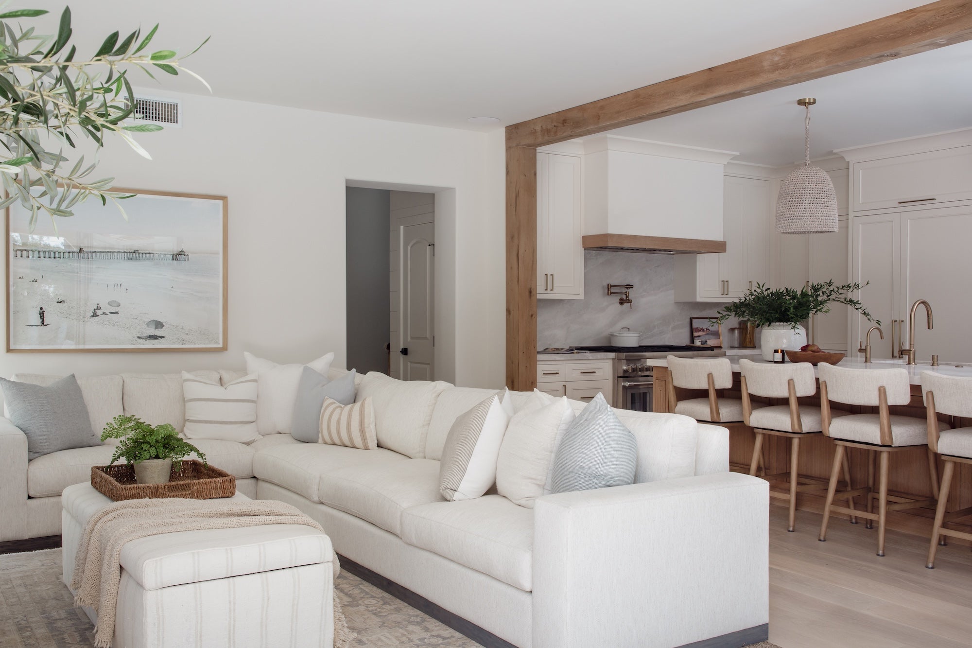 Living room with white sofa, coffee table, and kitchen in the background.