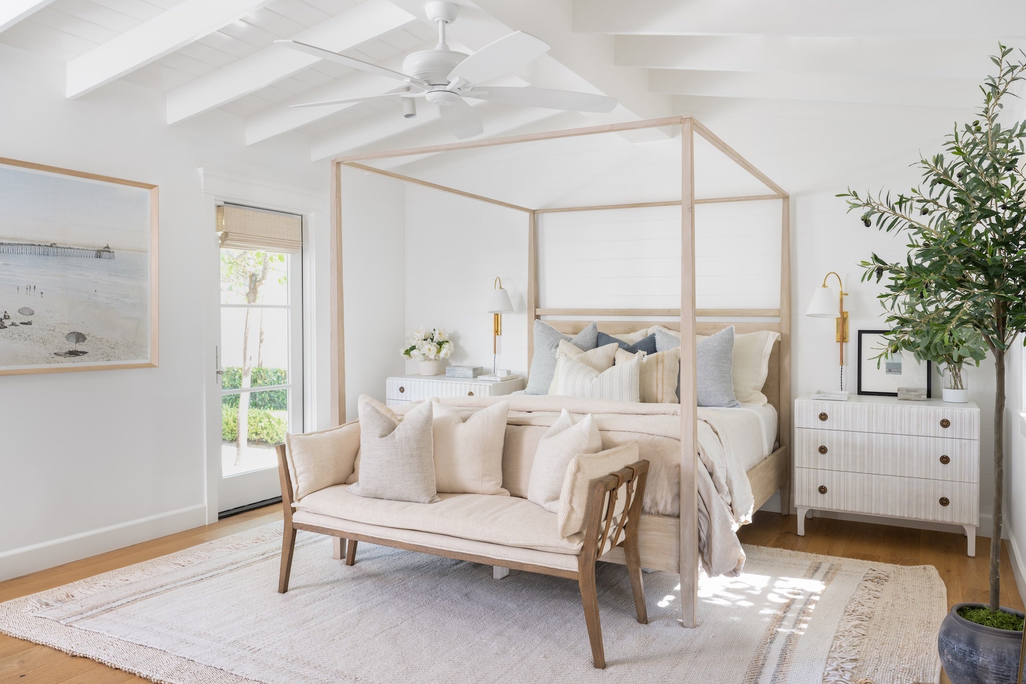 Neatly arranged bedroom with a canopy bed, bench, and decorative items.