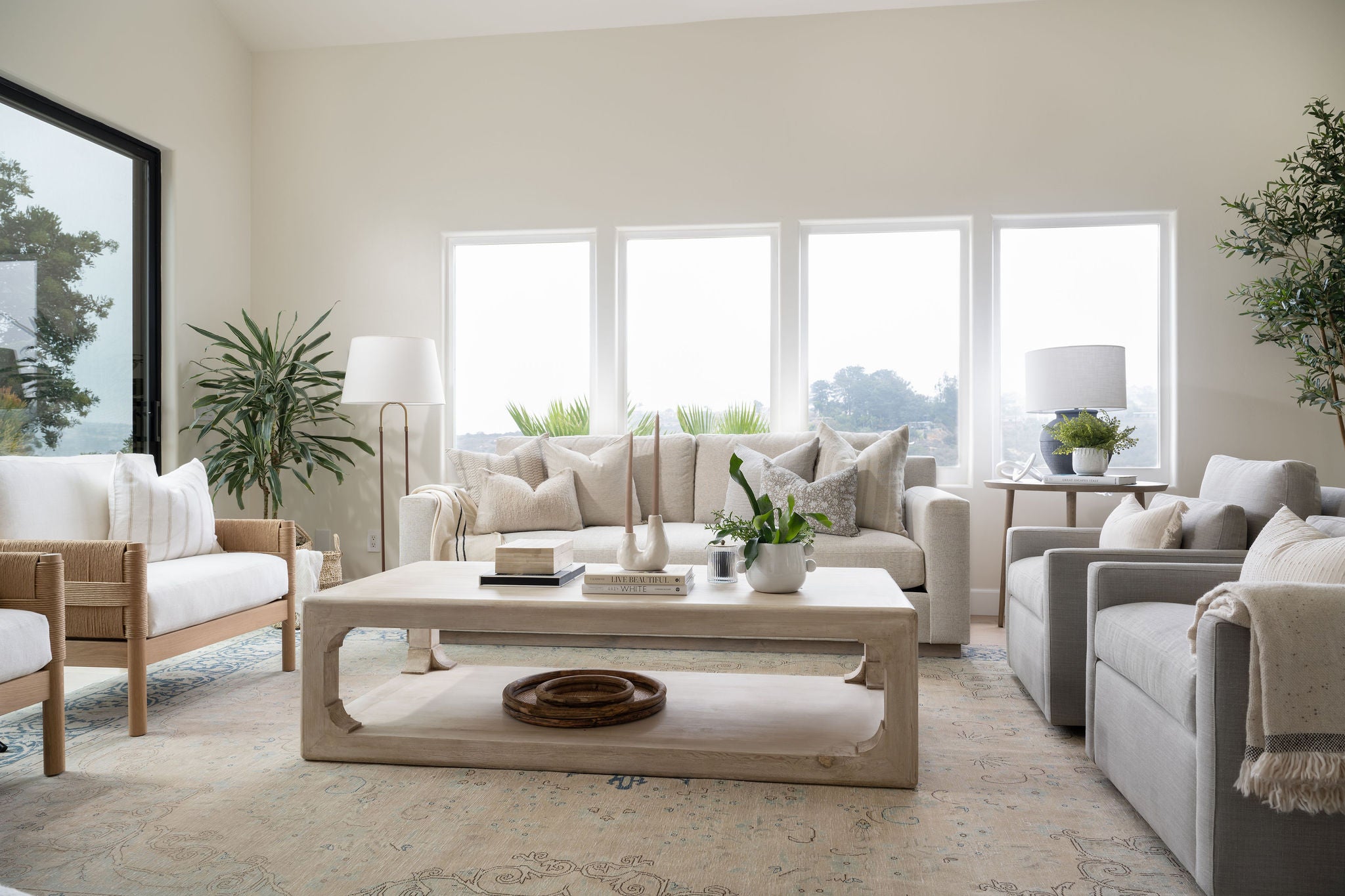 Living room with neutral seating, wood coffee table, and large windows with outdoor view.