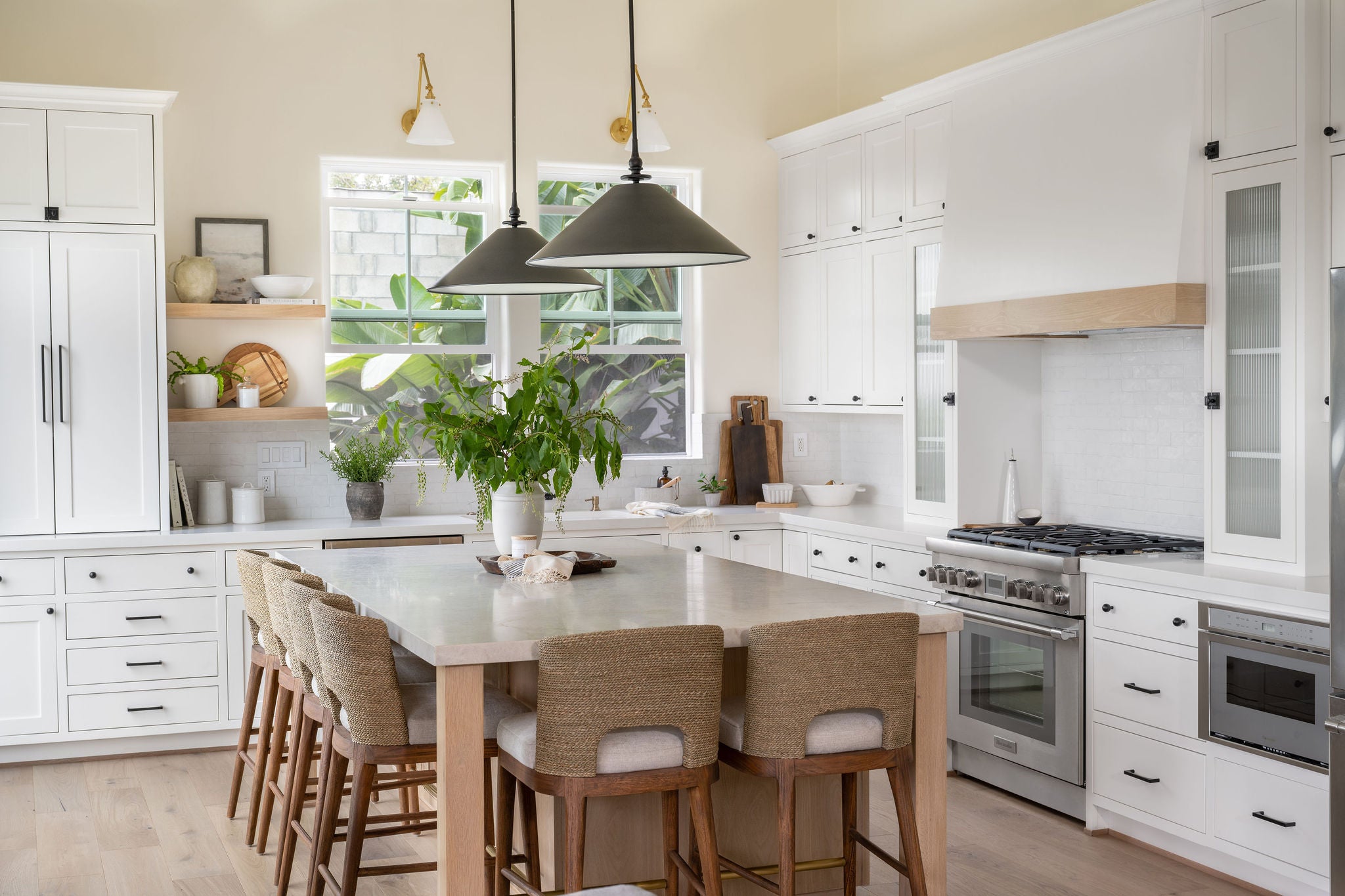 Modern kitchen with white cabinets, marble countertops, and wooden chairs.