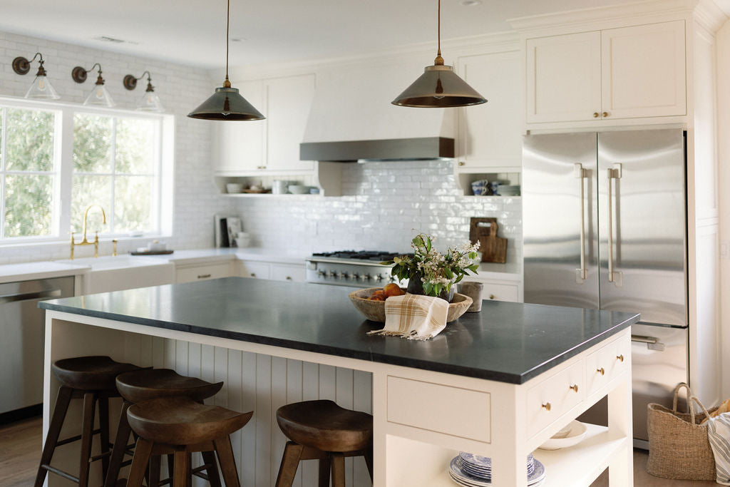 Bright kitchen with white tile backsplash and dark range hood.