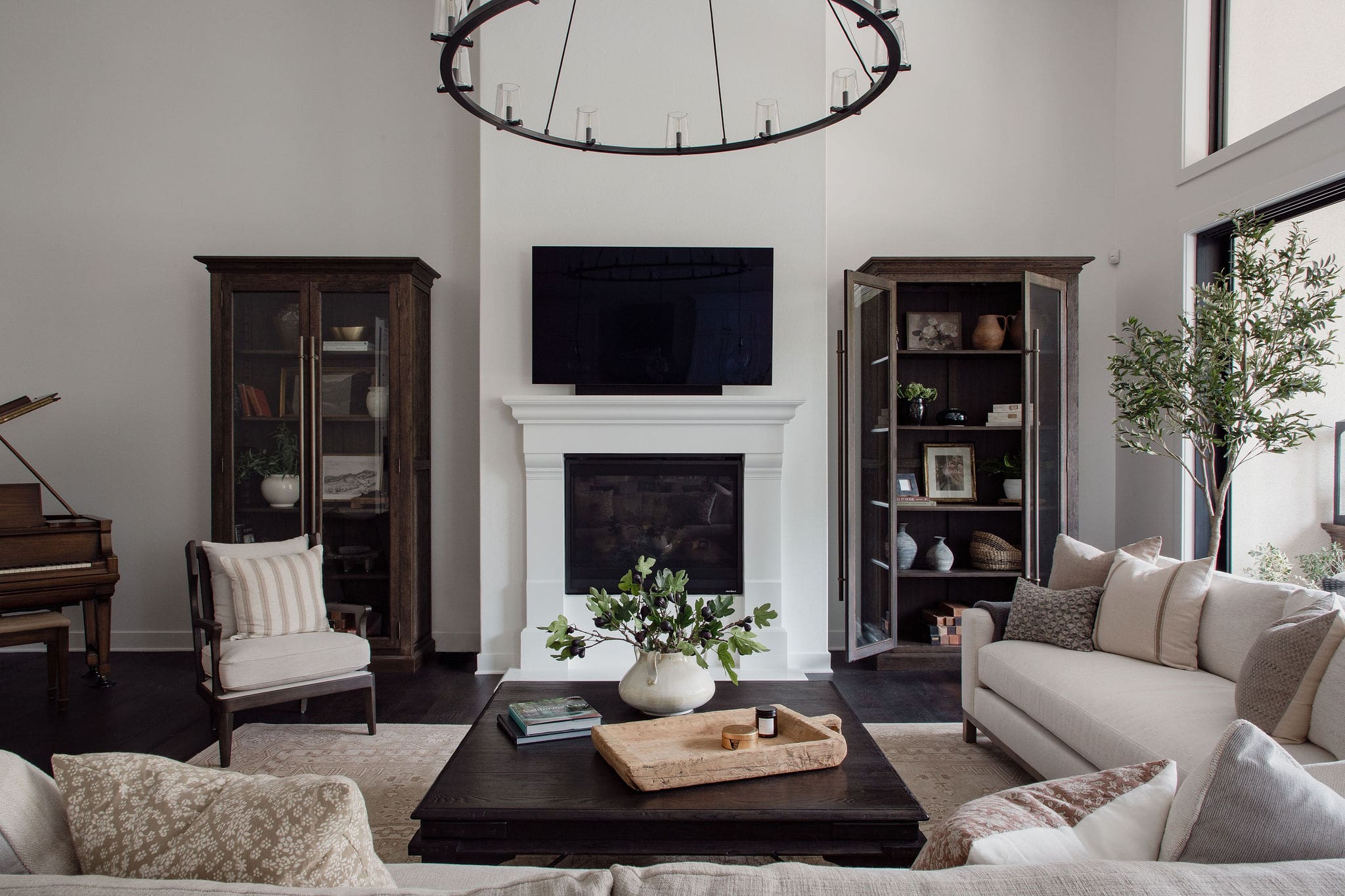 Living room with white fireplace, mounted TV, and tall wood display cabinets.