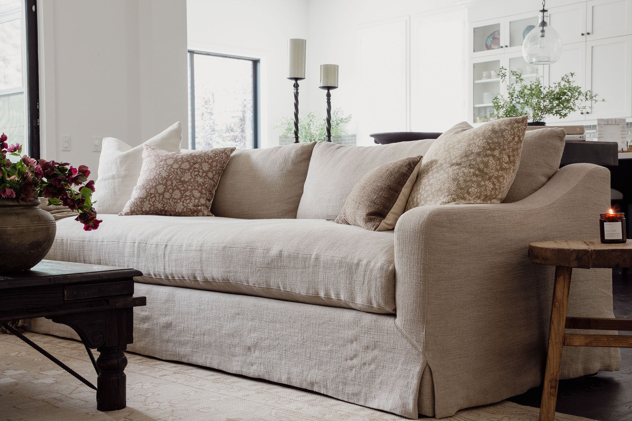 Neutral upholstered sofa with layered throw pillows and wood side table.